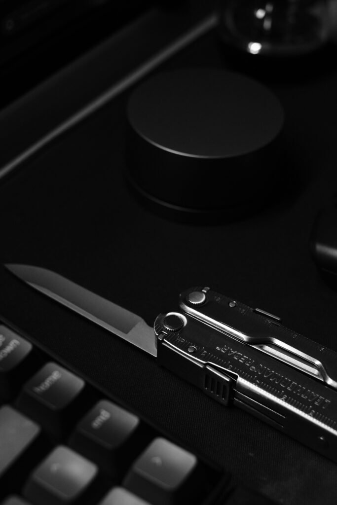 Stylish black and white shot of modern tech accessories and knife on a desk.