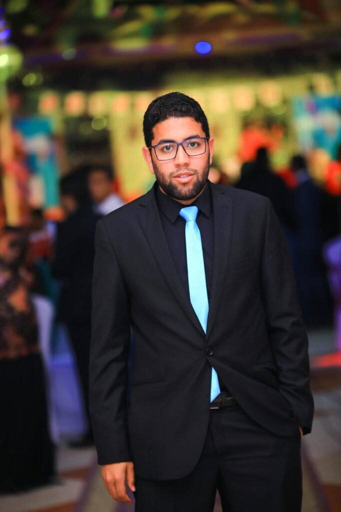 Portrait of a young man in a suit at a vibrant indoor event with bright decor.